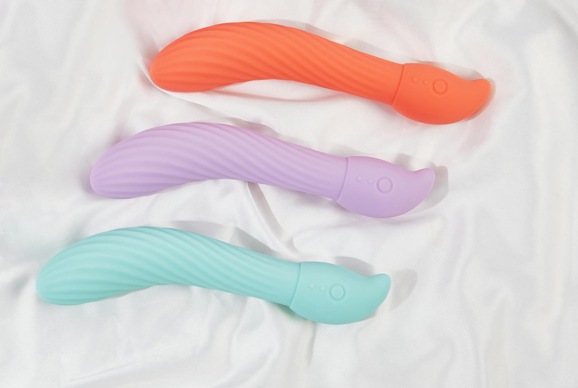 Three smooth colorful clitoral vibrators arranged on white fabric, representing different sensations across cycle phases.