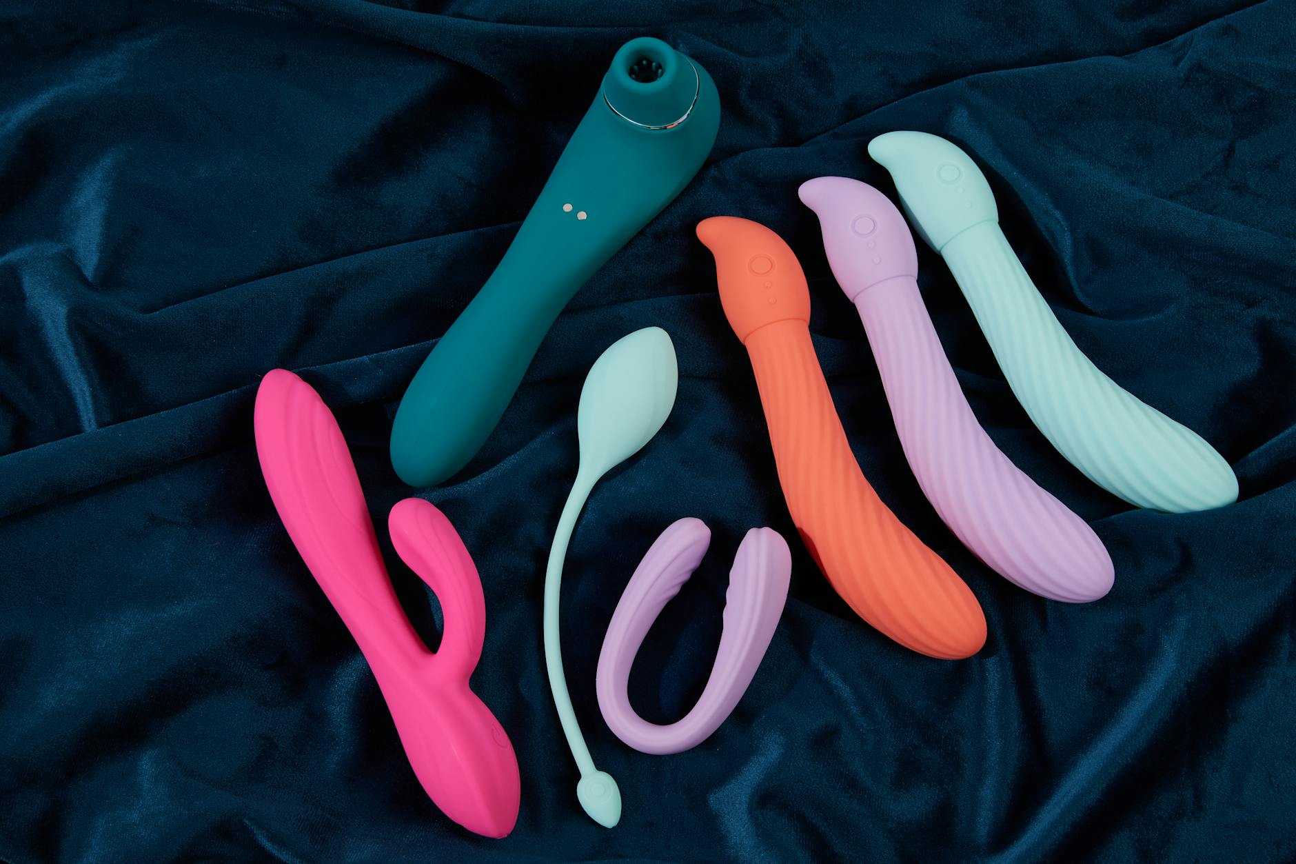 Colorful silicone vibrators on dark fabric, representing modern intimacy tools for reconnection