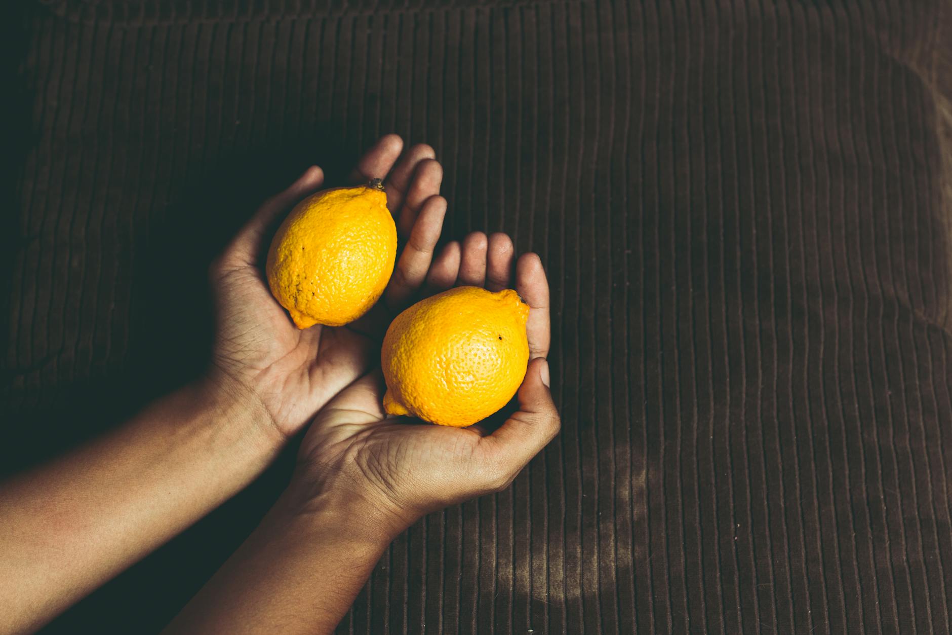 A hand holding a lemon against a vivid yellow background, representing renewal and freshness