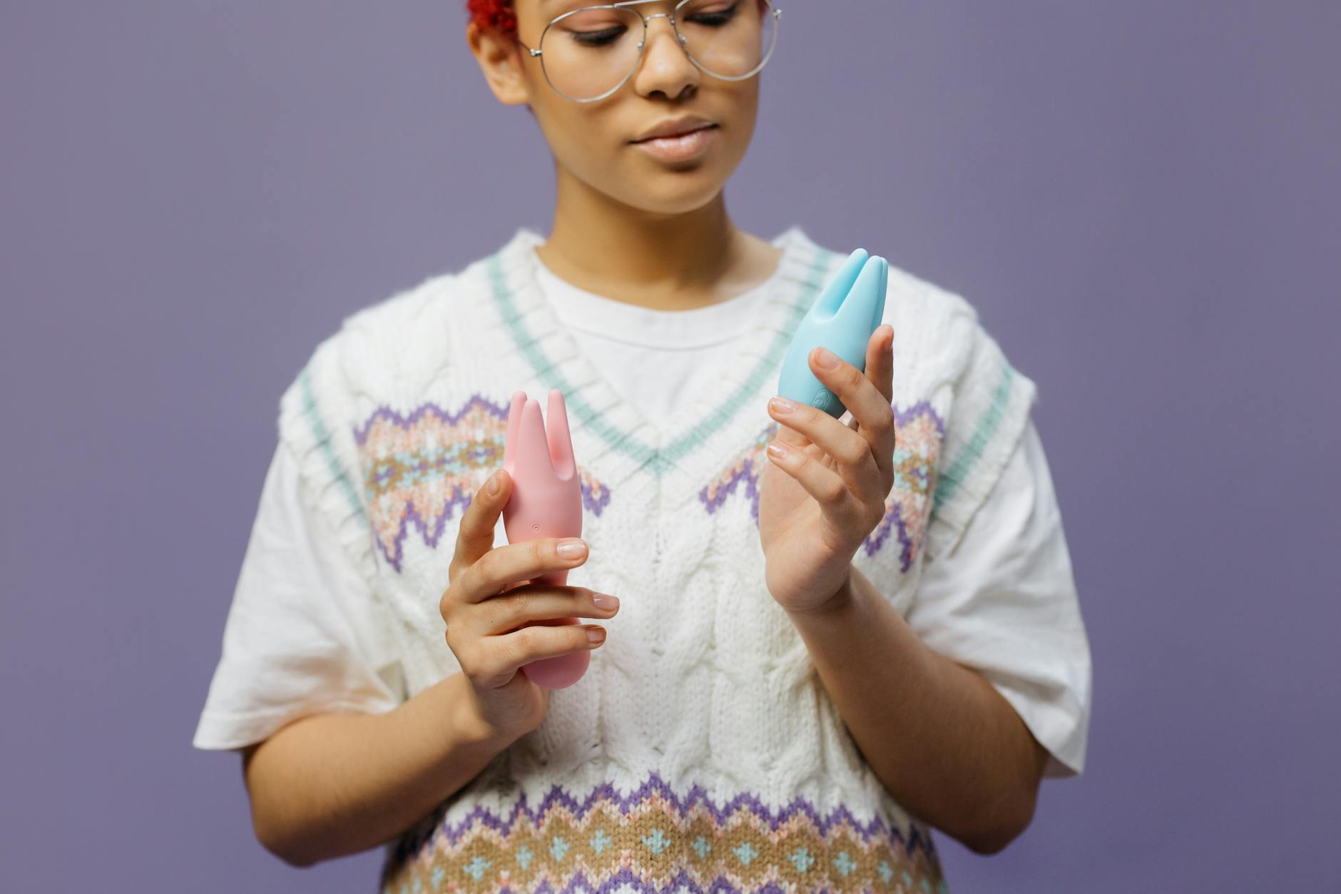Woman with eyeglasses considering different clitoral vibrators and contemplating pleasure options.
