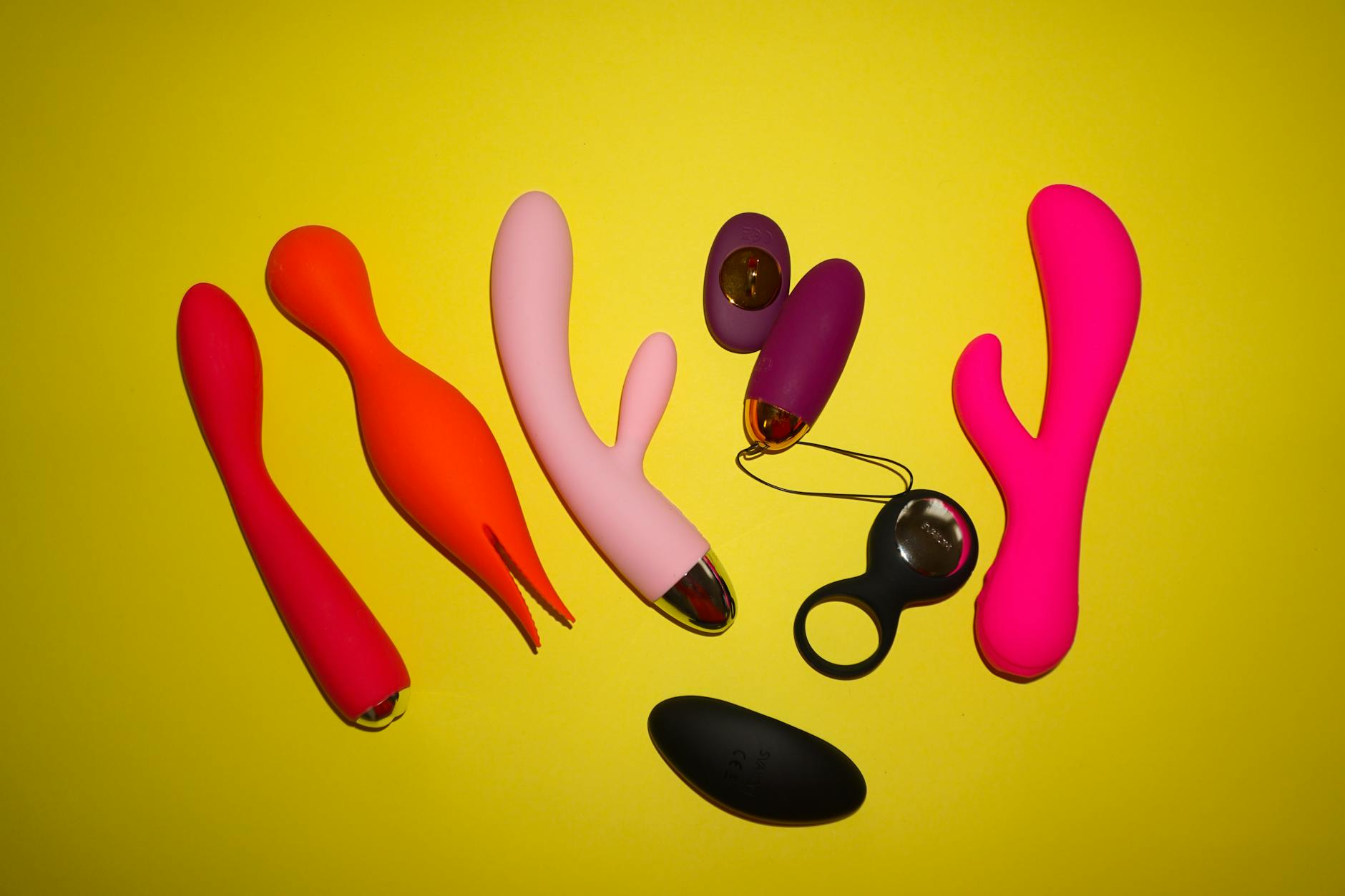 Woman holding a pink vibrator with art books in the background, representing reclaimed pleasure and self-care